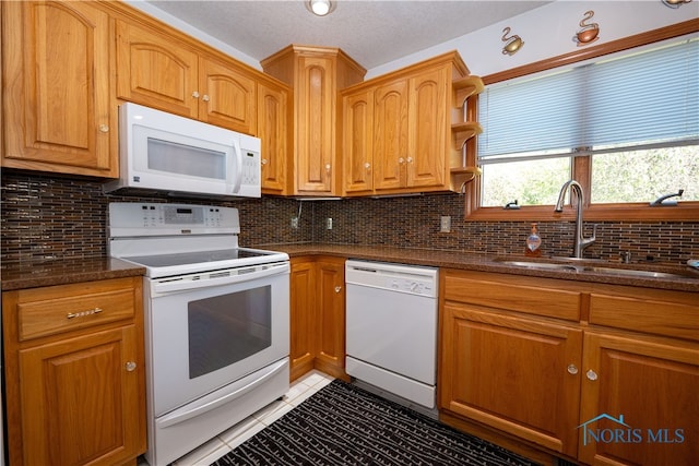 kitchen with decorative backsplash, sink, dark stone counters, and white appliances