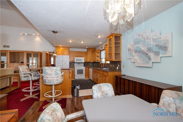 kitchen featuring a breakfast bar area, backsplash, wood-type flooring, sink, and white appliances