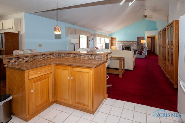 kitchen with ceiling fan, vaulted ceiling, light tile patterned flooring, a fireplace, and decorative light fixtures