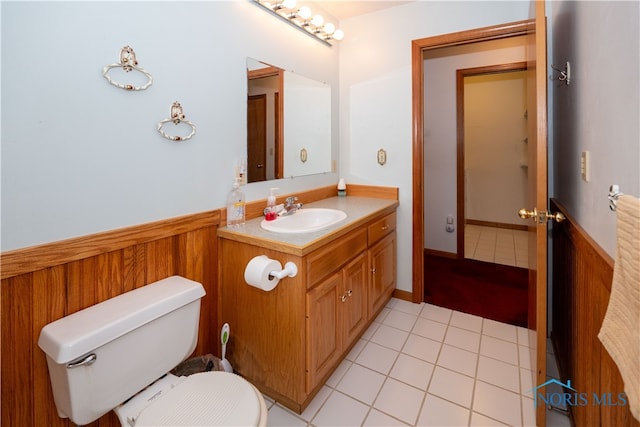 bathroom with vanity, wooden walls, toilet, and tile patterned flooring