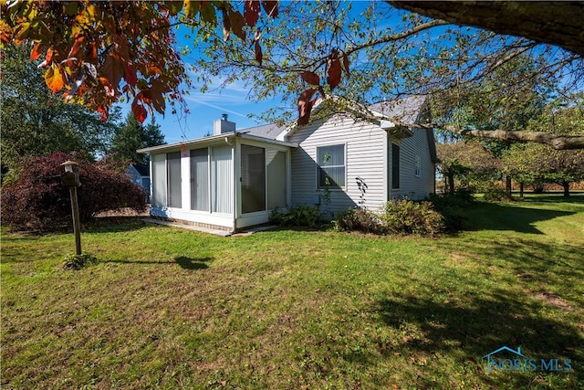 rear view of property featuring a yard and a sunroom