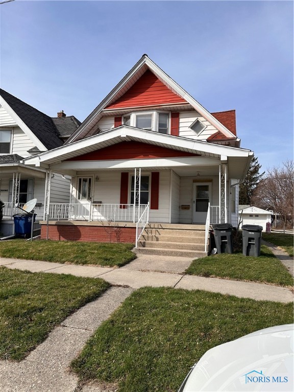 view of front of property featuring a porch, a front lawn, and a garage