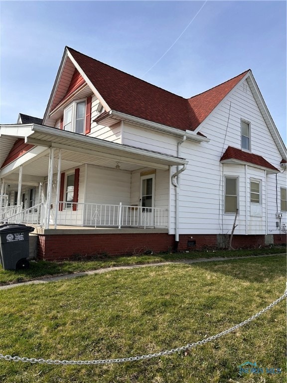 view of side of property with a porch and a lawn