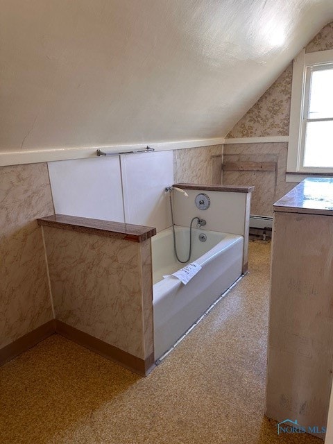 bathroom with a tub and vaulted ceiling