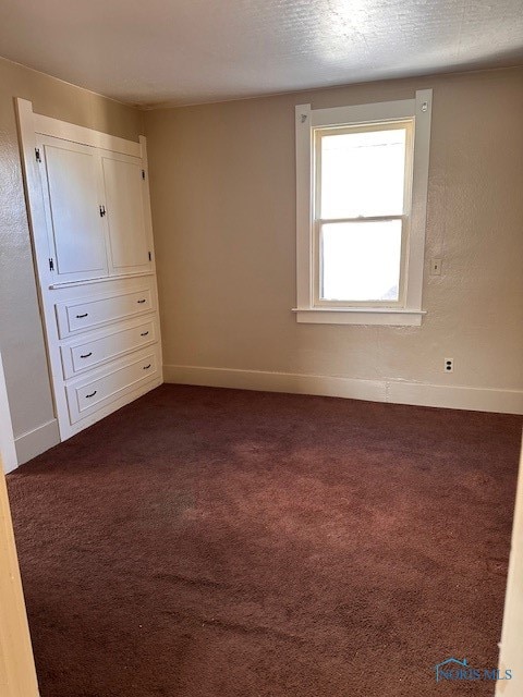 unfurnished bedroom featuring dark carpet and a textured ceiling