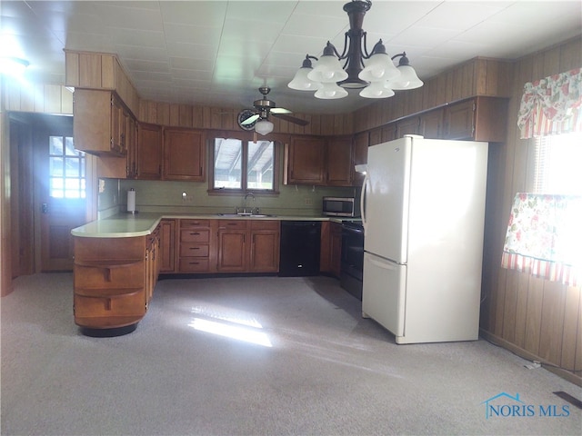 kitchen featuring ceiling fan with notable chandelier, light carpet, decorative light fixtures, sink, and black appliances