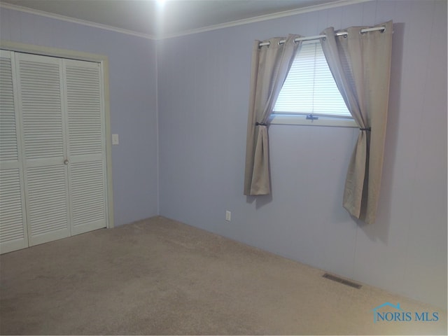 unfurnished bedroom with a closet, crown molding, and carpet flooring