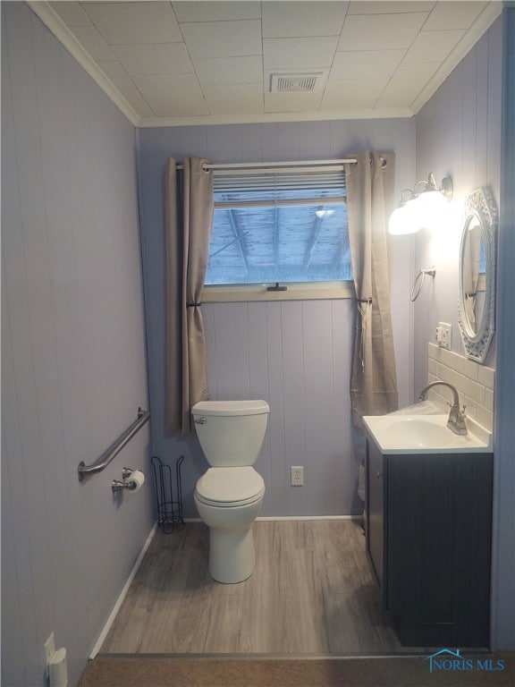 bathroom featuring hardwood / wood-style floors, vanity, wood walls, and toilet