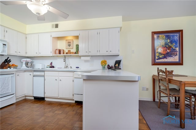 kitchen featuring dark parquet flooring, white cabinetry, kitchen peninsula, and white appliances