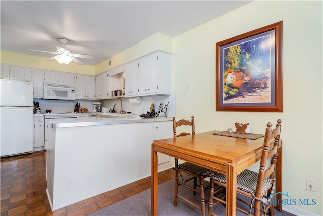 kitchen featuring white appliances, sink, dark parquet floors, kitchen peninsula, and white cabinets