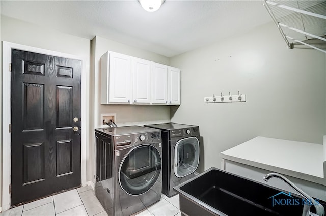 clothes washing area featuring sink, light tile patterned flooring, cabinets, and separate washer and dryer