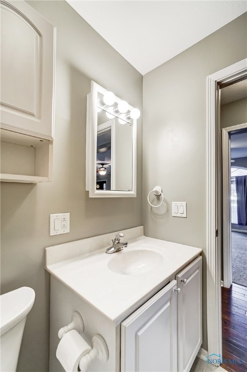 bathroom with toilet, hardwood / wood-style floors, and vanity