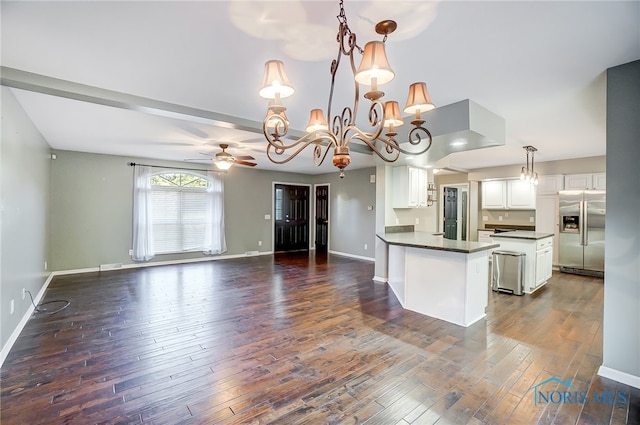 kitchen featuring dark wood-type flooring, stainless steel fridge, pendant lighting, white cabinetry, and ceiling fan with notable chandelier