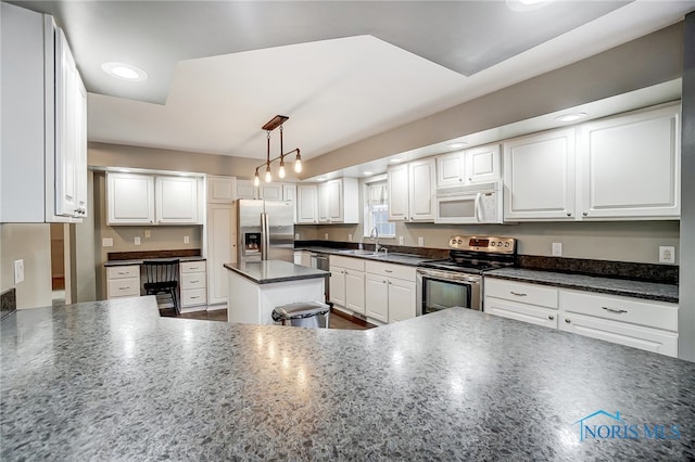 kitchen with white cabinetry, stainless steel appliances, hanging light fixtures, and sink