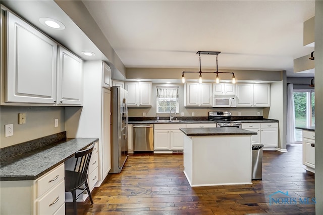 kitchen with dark hardwood / wood-style floors, appliances with stainless steel finishes, decorative light fixtures, and a kitchen island