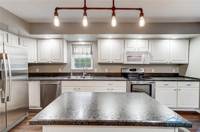 kitchen with a kitchen island, appliances with stainless steel finishes, sink, dark wood-type flooring, and decorative light fixtures