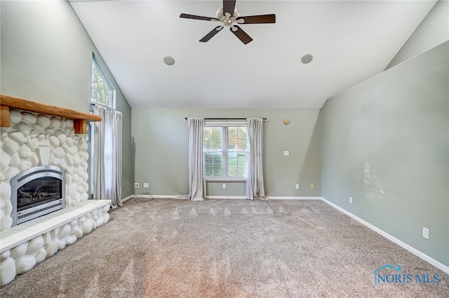 unfurnished living room featuring vaulted ceiling, a fireplace, carpet floors, and plenty of natural light