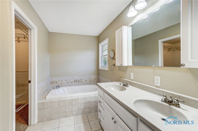 bathroom featuring vanity, a relaxing tiled tub, and tile patterned floors