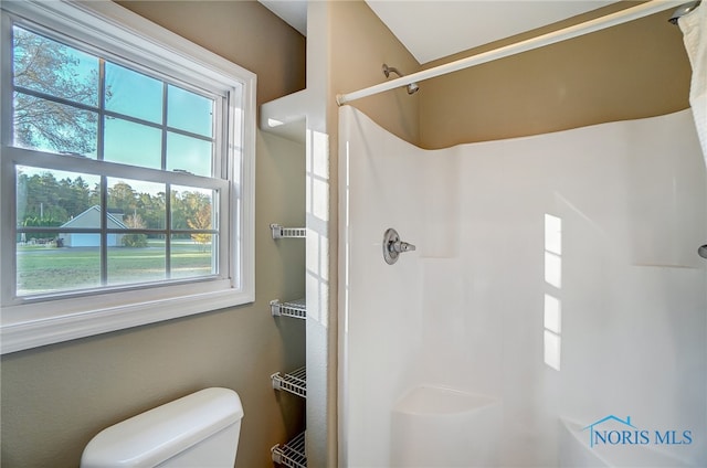 bathroom featuring toilet, a healthy amount of sunlight, and curtained shower