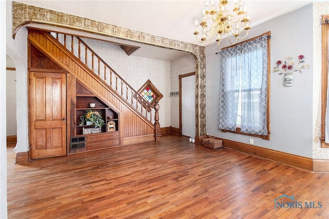 unfurnished living room with hardwood / wood-style flooring and a chandelier