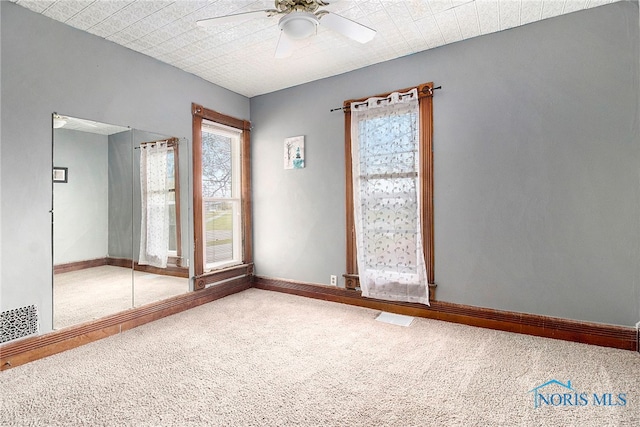 carpeted spare room with ceiling fan