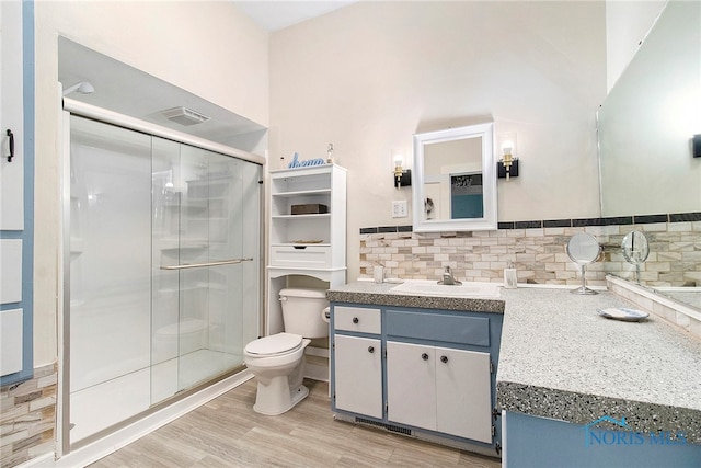 bathroom with vanity, backsplash, hardwood / wood-style flooring, toilet, and walk in shower