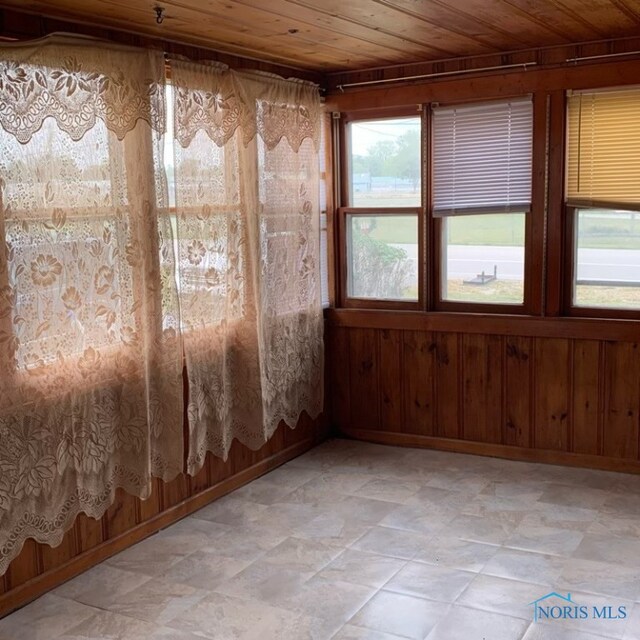 empty room featuring wood walls and wooden ceiling