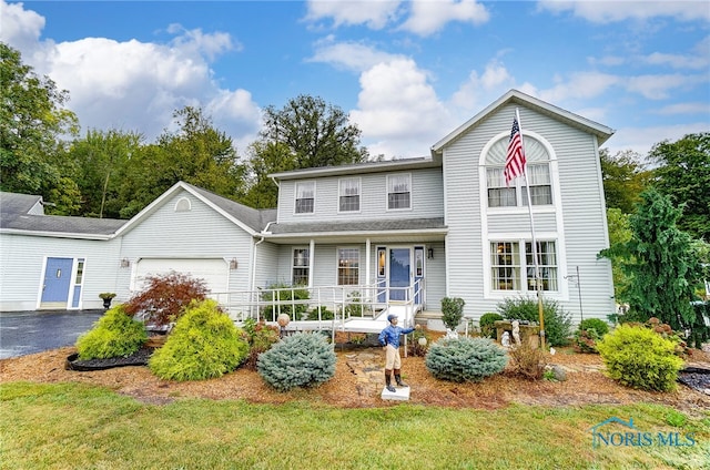 front facade featuring a porch, a front lawn, and a garage