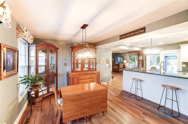 dining area with sink, a notable chandelier, and light wood-type flooring