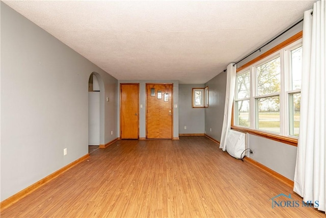 spare room featuring light wood-type flooring, a textured ceiling, and radiator heating unit