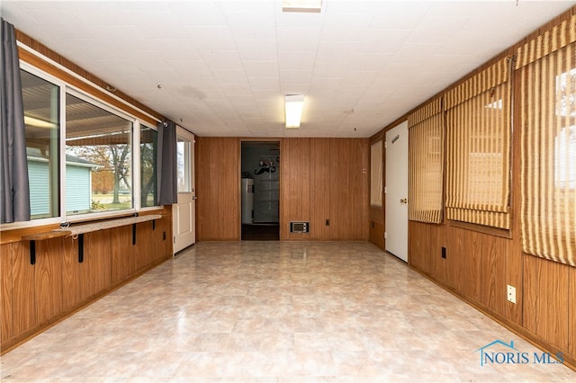 spare room featuring wood walls and electric water heater