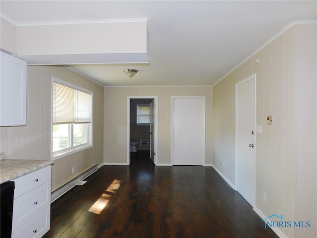 unfurnished dining area with built in desk, a baseboard radiator, dark wood-type flooring, and crown molding