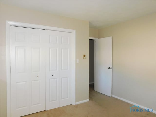 unfurnished bedroom featuring a closet and light colored carpet