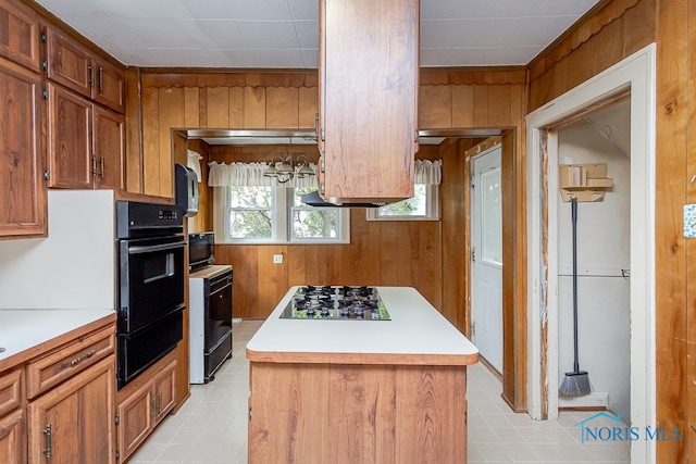 kitchen with wooden walls, a center island, and black appliances