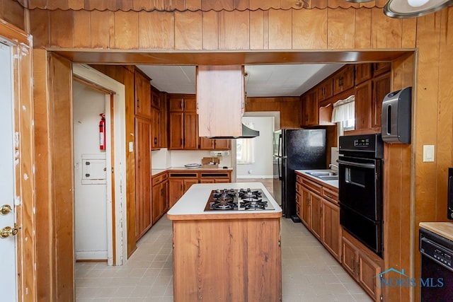 kitchen featuring wood walls, black appliances, and a center island