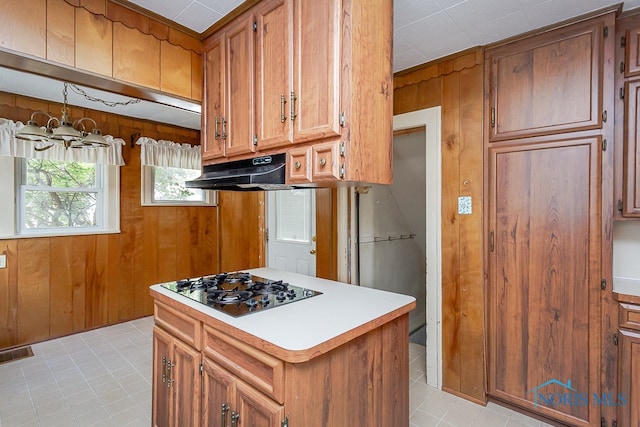 kitchen with gas stovetop, wooden walls, hanging light fixtures, light tile patterned flooring, and a notable chandelier