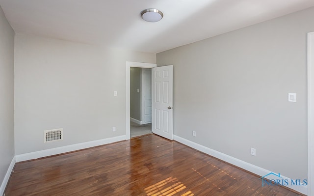 unfurnished room with dark wood-type flooring