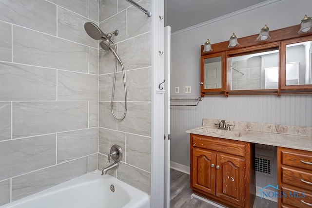 bathroom with vanity, crown molding, wood-type flooring, and tiled shower / bath