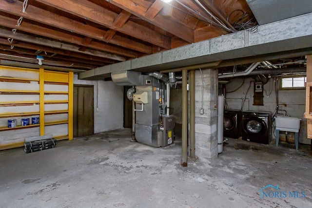 basement featuring sink, heating unit, and washing machine and clothes dryer