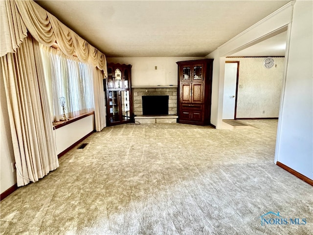 unfurnished living room with a textured ceiling, carpet floors, and a fireplace