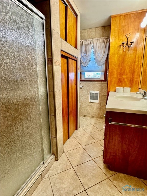 bathroom with heating unit, tile walls, vanity, an enclosed shower, and tile patterned floors