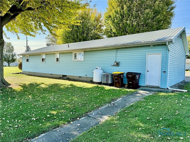 rear view of property featuring central air condition unit and a lawn