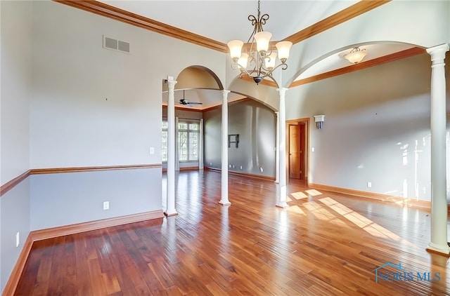 spare room featuring crown molding, hardwood / wood-style flooring, ceiling fan with notable chandelier, and ornate columns