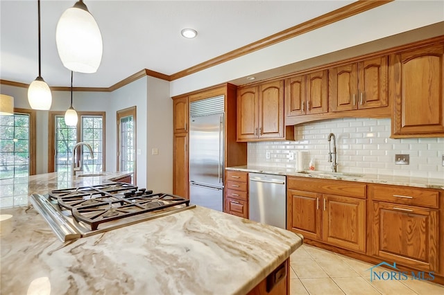 kitchen featuring sink, light stone counters, appliances with stainless steel finishes, and hanging light fixtures