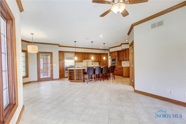 kitchen featuring a center island with sink, pendant lighting, and a healthy amount of sunlight