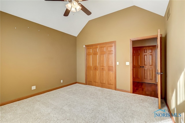 unfurnished bedroom with carpet, a closet, vaulted ceiling, and ceiling fan