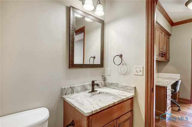 bathroom featuring toilet, ornamental molding, vanity, and wood-type flooring