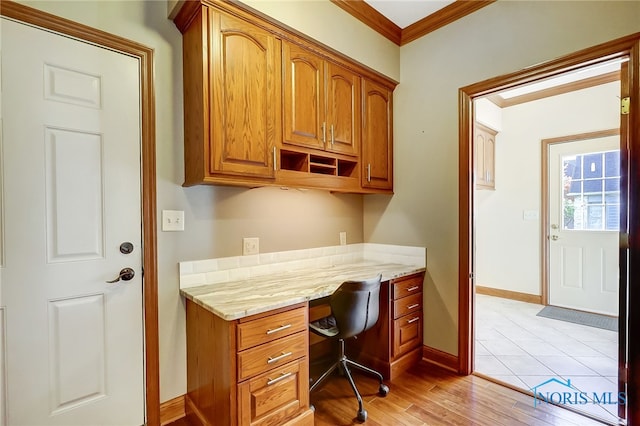 office space with crown molding, built in desk, and light wood-type flooring