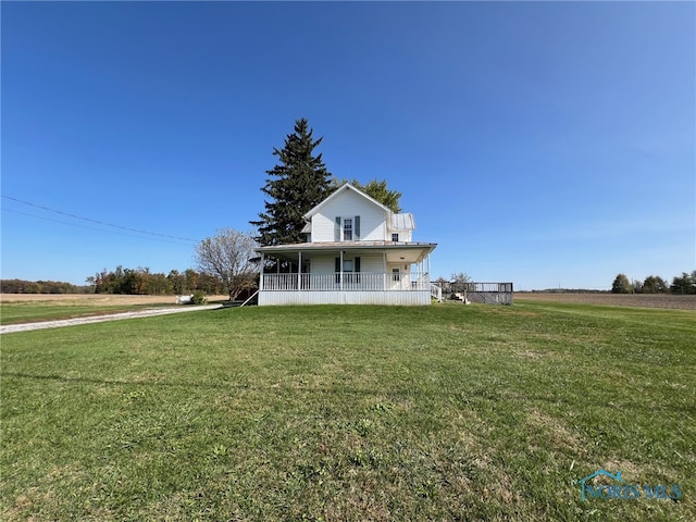 farmhouse inspired home with a rural view, covered porch, and a front lawn