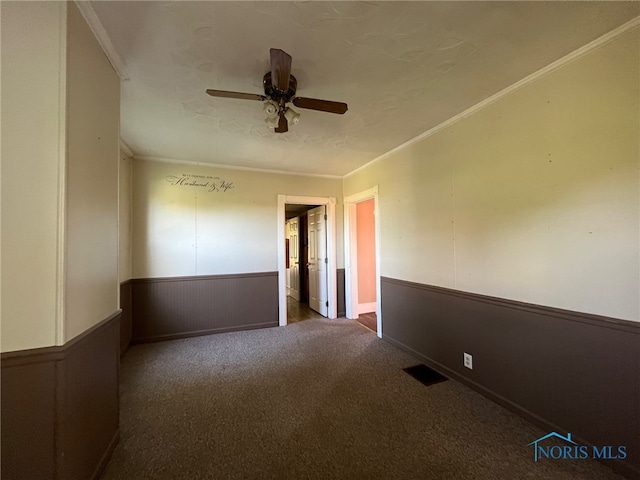 spare room with ornamental molding, dark carpet, and ceiling fan